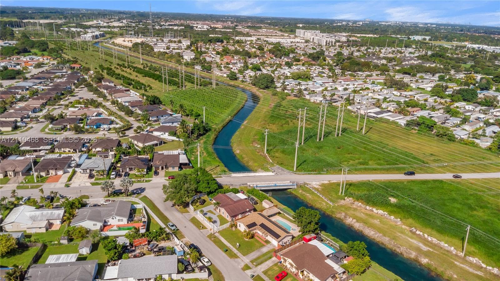Aerial perspective of a suburban neighborhood featuring a canal, paved street infrastructure, and established residential lots