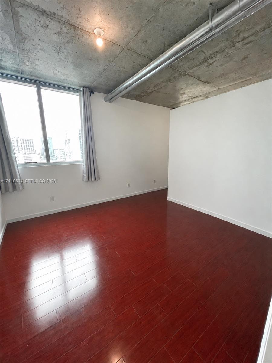 Exposed concrete ceiling, dark wood-finish flooring, floor-to-ceiling windows, and double-door closet