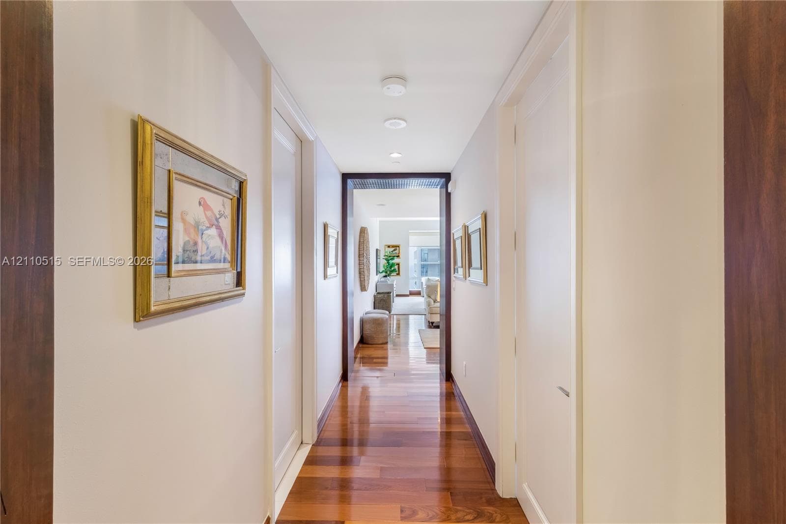 Hallway featuring wood-finish flooring, recessed ceiling lighting, and dark-toned door casings