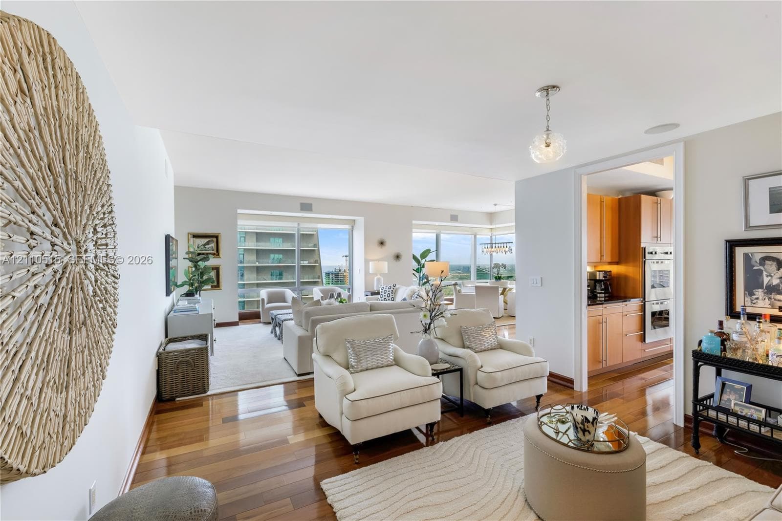 Polished wood-finish flooring, floor-to-ceiling windows, and natural light exposure, with built-in cabinetry and stainless steel wall-mounted oven in the kitchen