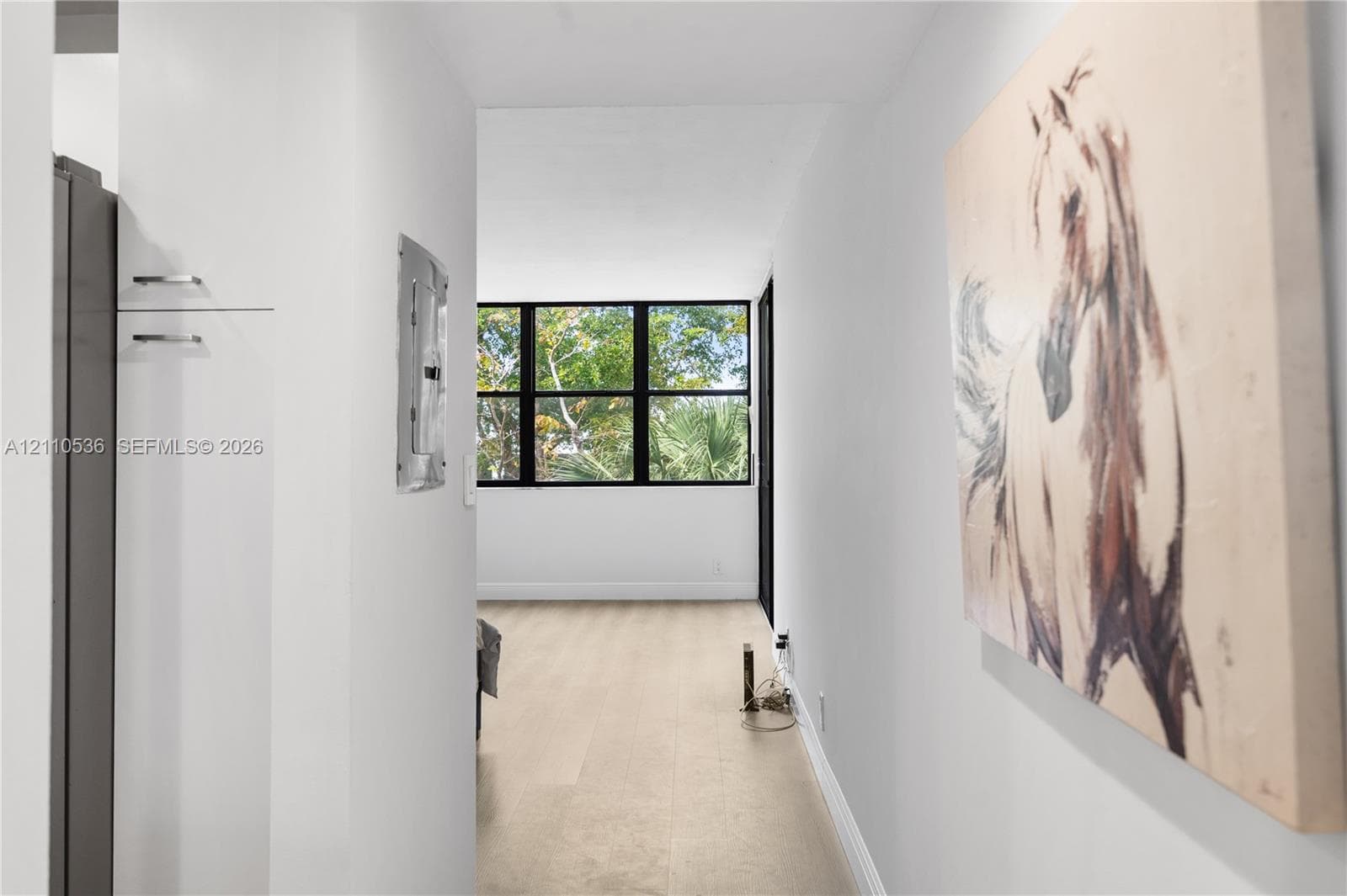 Interior hallway featuring neutral walls, light-toned flooring, and black-framed windows