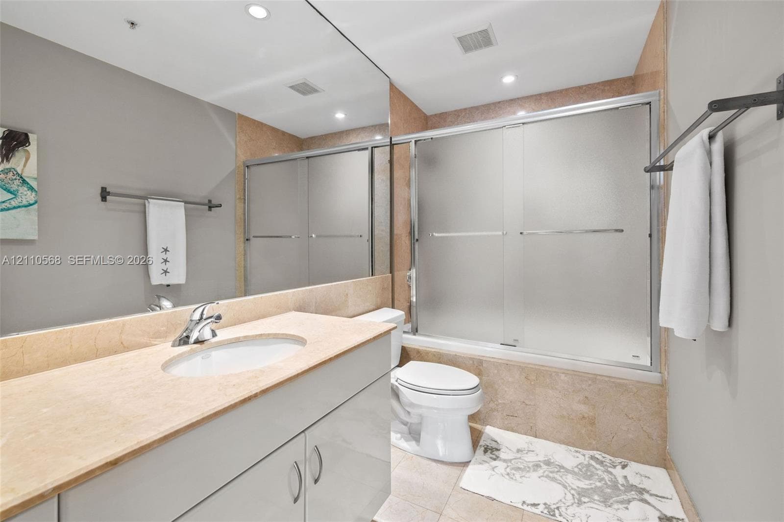 Bathroom featuring a vanity with a stone countertop, an integrated sink, full-width wall mirror, and a tub-shower combination with sliding frosted-glass doors