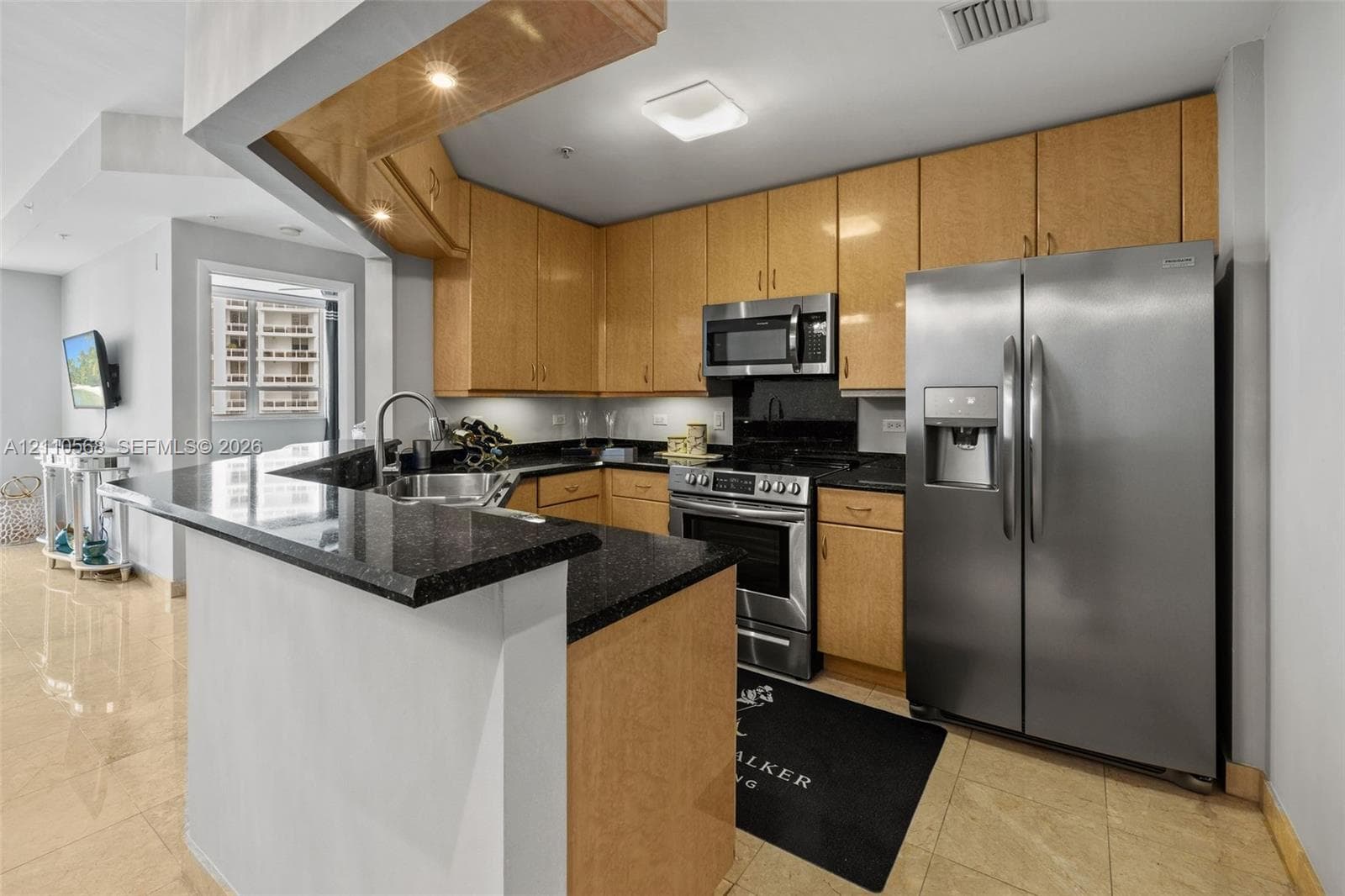 Kitchen featuring light-finish cabinetry, dark solid-surface countertops, stainless steel appliances, and tiled flooring