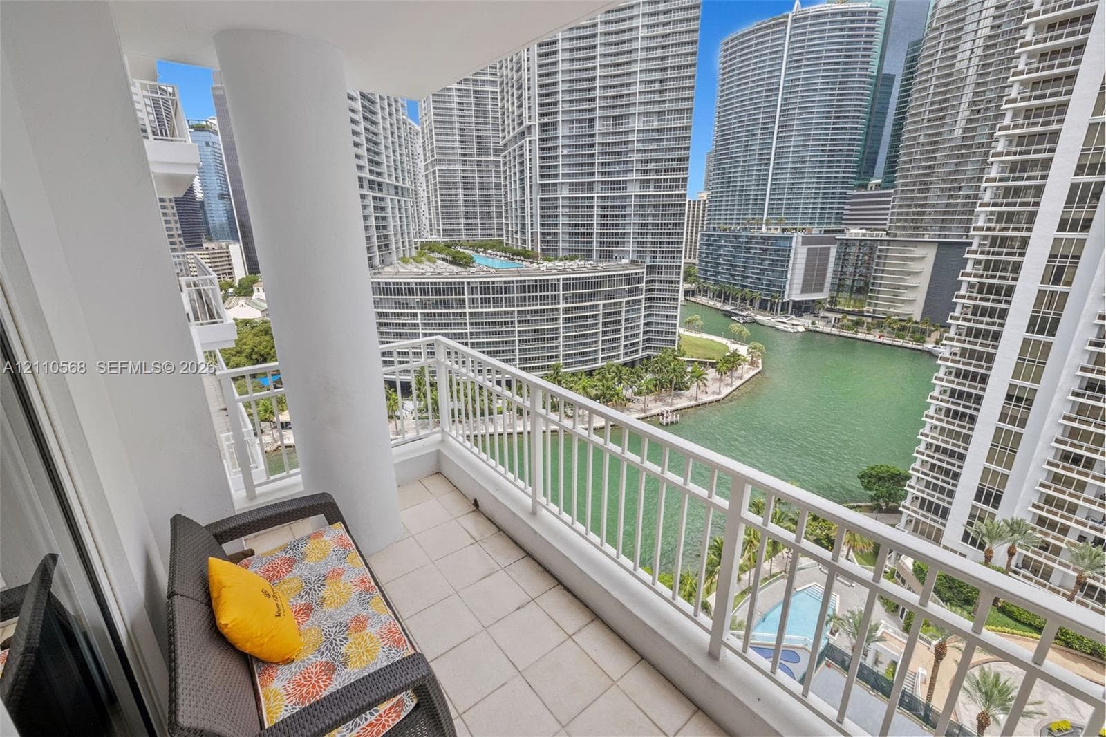 Covered balcony with white tile flooring, structural pillar, and white metal railing