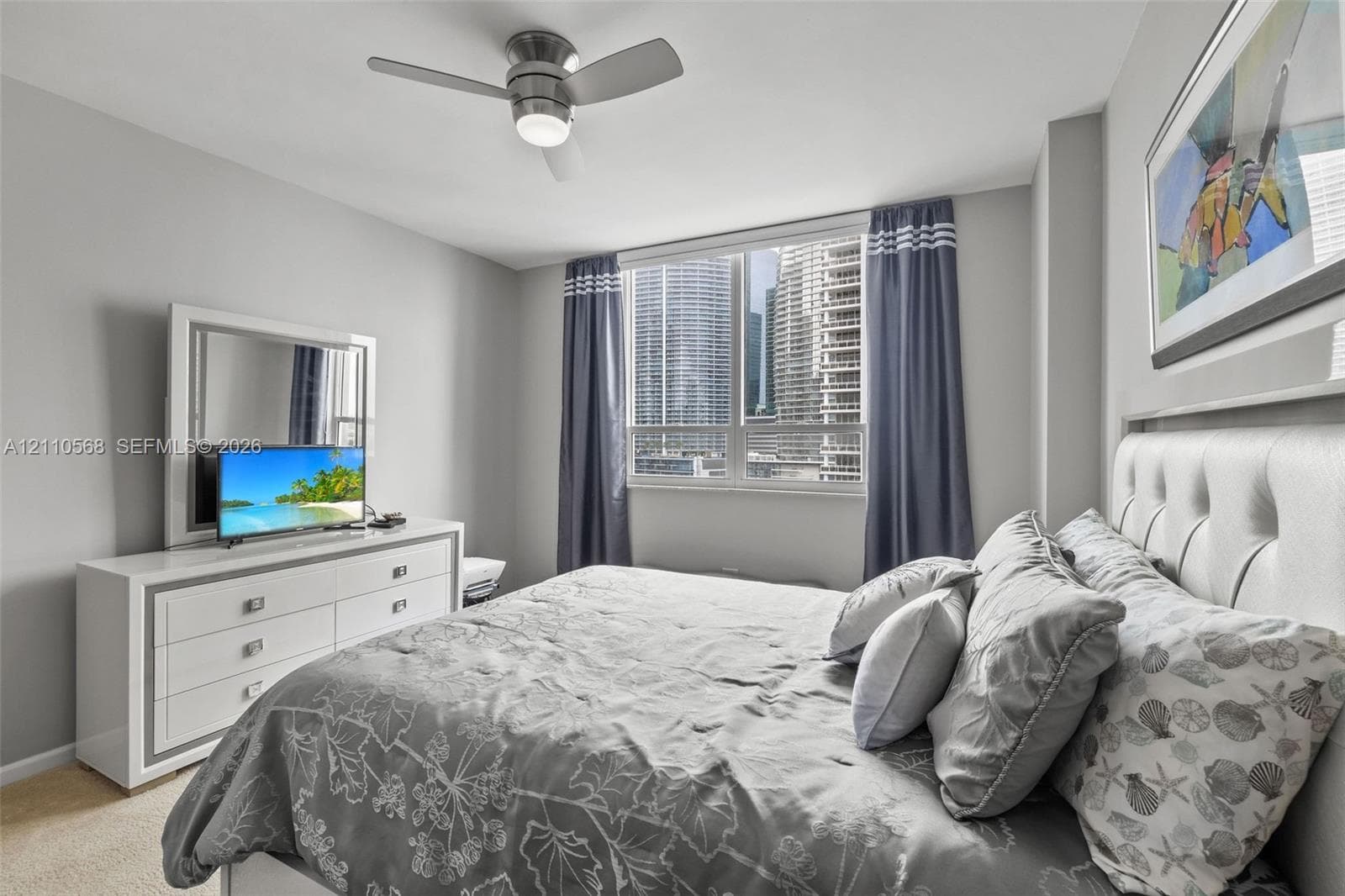 Neutral-toned interior featuring a ceiling fan with integrated lighting and a large window with urban exterior exposure