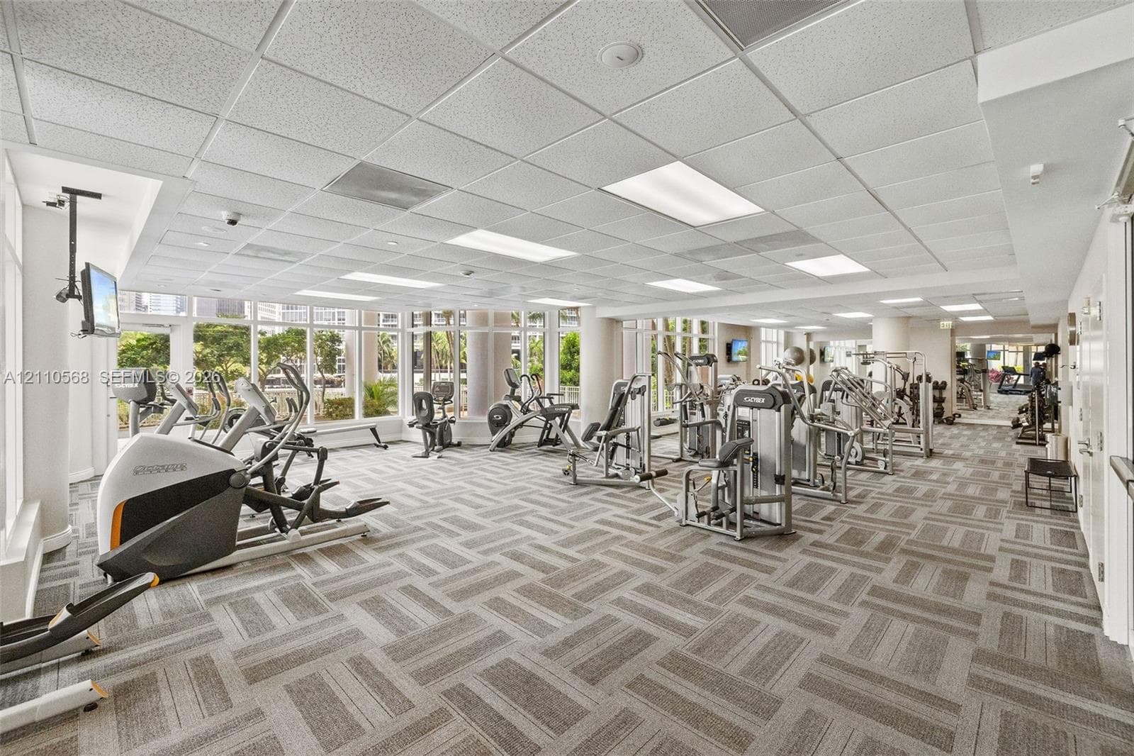 Fitness facility featuring a drop ceiling with recessed lighting, wall-to-wall carpeted flooring, and floor-to-ceiling windows