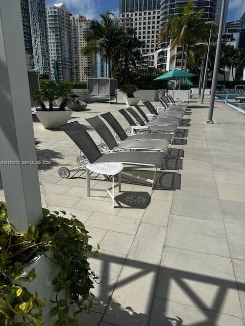 Pool deck featuring light-toned stone paving, metal structures, and large ornamental planters