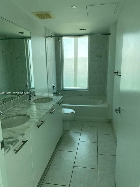 Dual-sink vanity with stone-finish countertop, white cabinetry, large wall-mounted mirror, ceramic tile flooring, and a shower-tub combination with tile surround