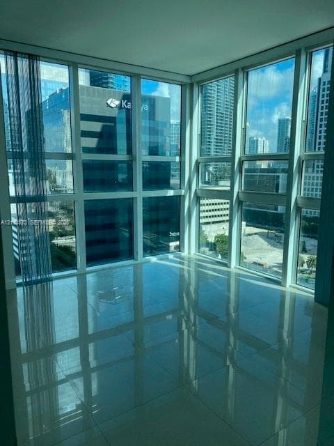 Floor-to-ceiling windows, corner orientation, polished tile flooring, and urban scenery