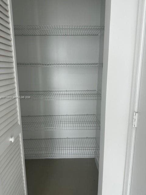 Storage closet featuring white louvered doors and five levels of white wire shelving