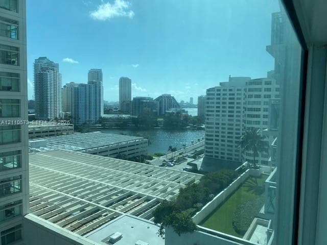 Floor-to-ceiling windows providing an urban landscape panorama, featuring expansive water scenery and surrounding mid-rise and high-rise structures