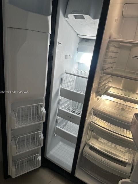 Side-by-side refrigerator featuring wire door baskets, adjustable wire shelving, integrated crisper drawers, and interior lighting