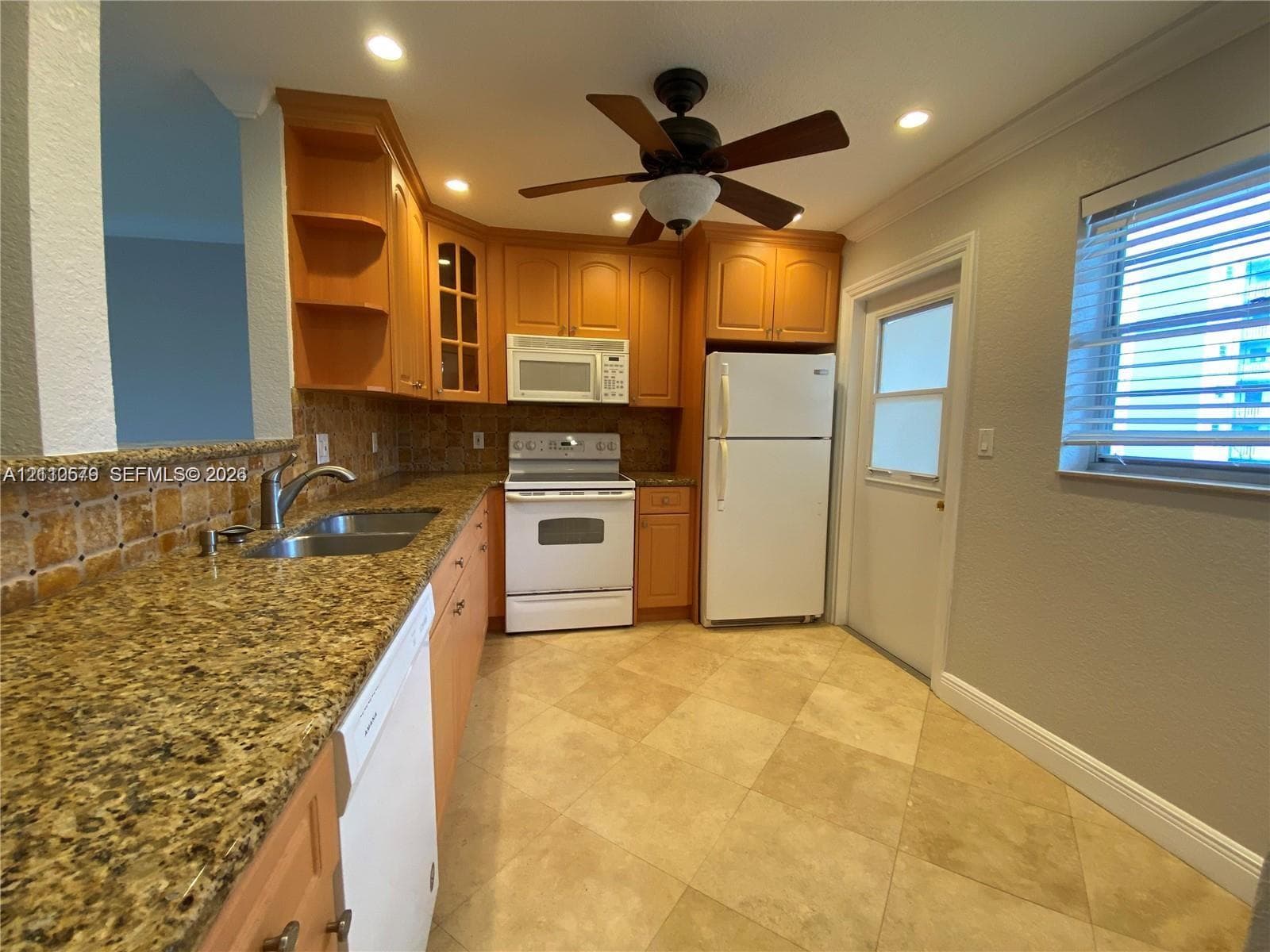 Kitchen featuring wood cabinetry, stone-surface countertops, stone tile backsplash, tile flooring, and integrated ceiling fan