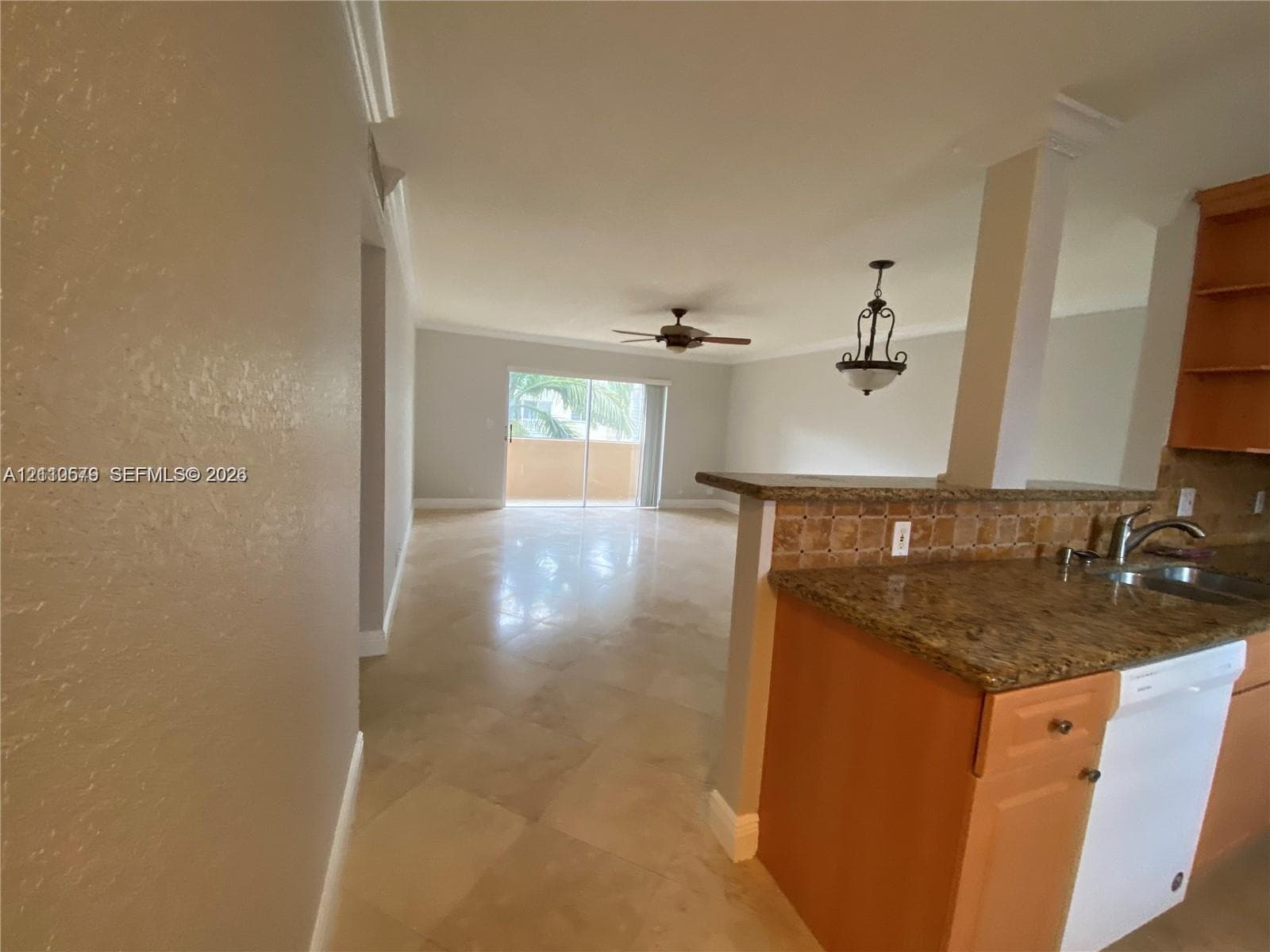 Open-concept interior featuring large-format tile flooring, a kitchen peninsula with stone-finish countertops, decorative tile backsplash, recessed ceiling fan, and sliding glass doors