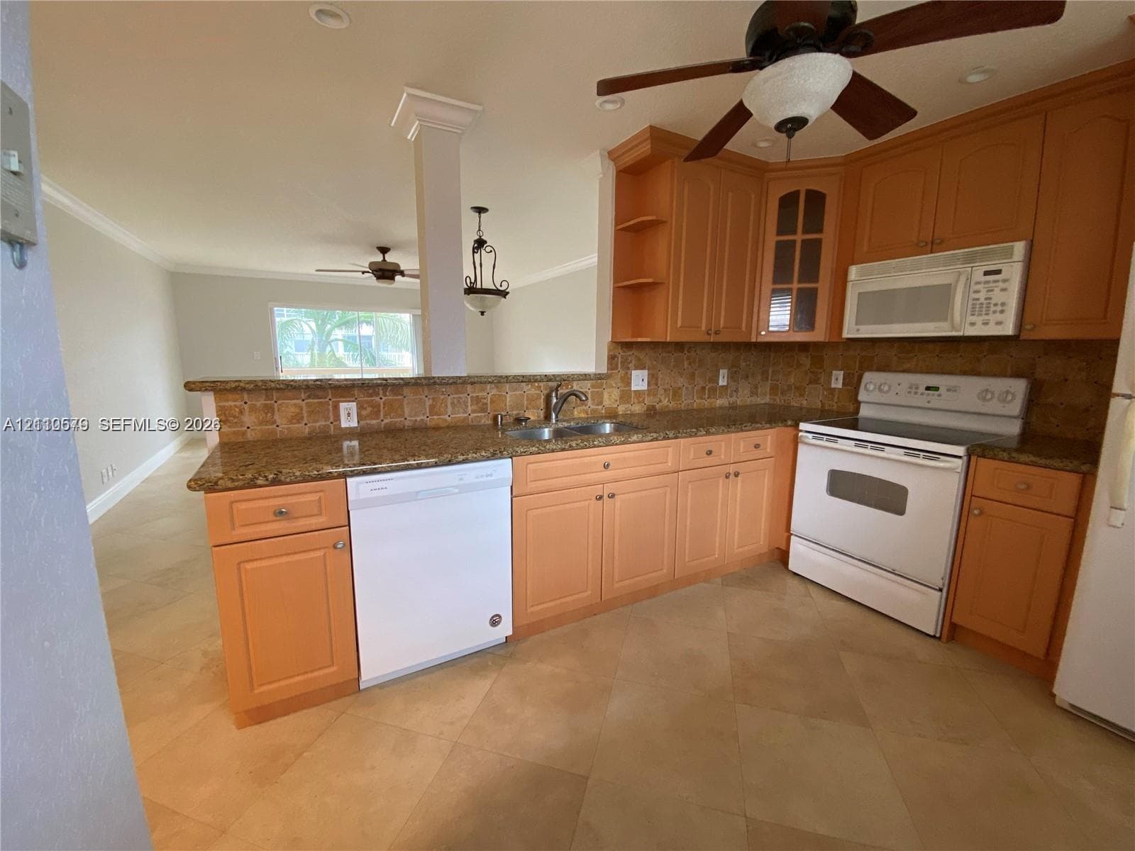 Kitchen featuring natural finish wood cabinetry, stone countertops, tiled backsplash, neutral tone tile flooring, and a ceiling-mounted fan with integrated lighting