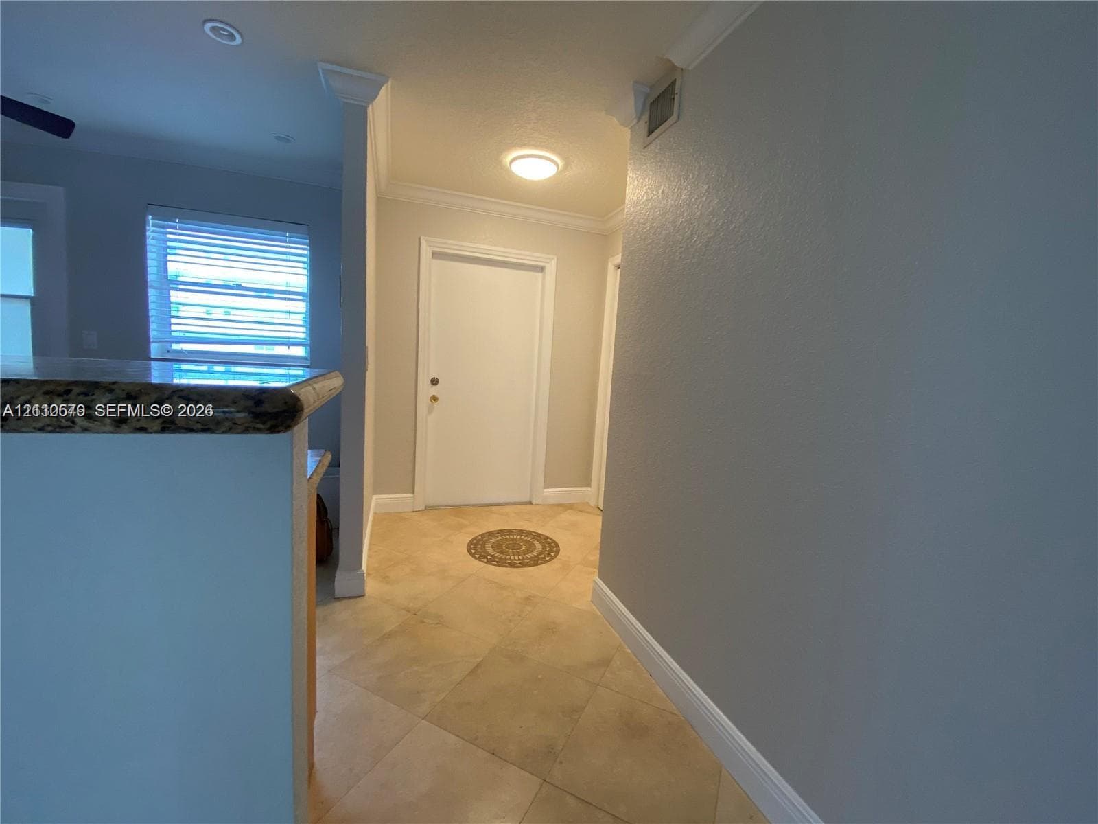 Entryway featuring tile flooring, crown molding, and a solid-panel door with architectural casing