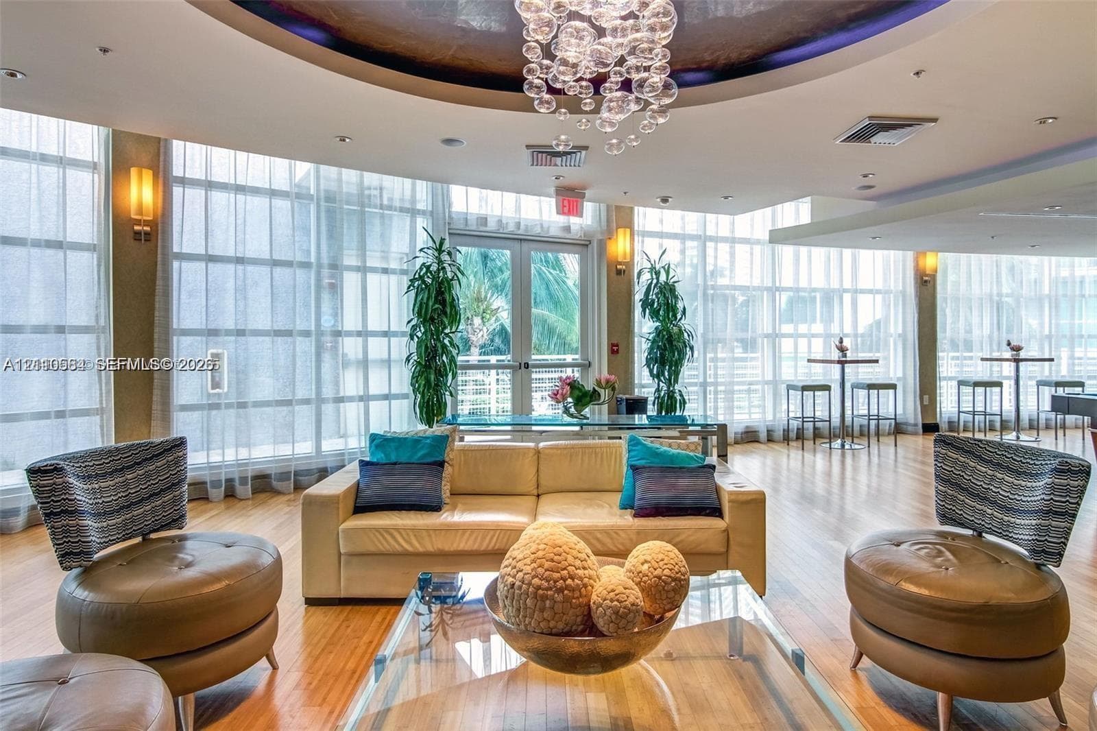 Floor-to-ceiling windows, circular recessed ceiling detail, wood-finish flooring, and built-in wall sconce lighting