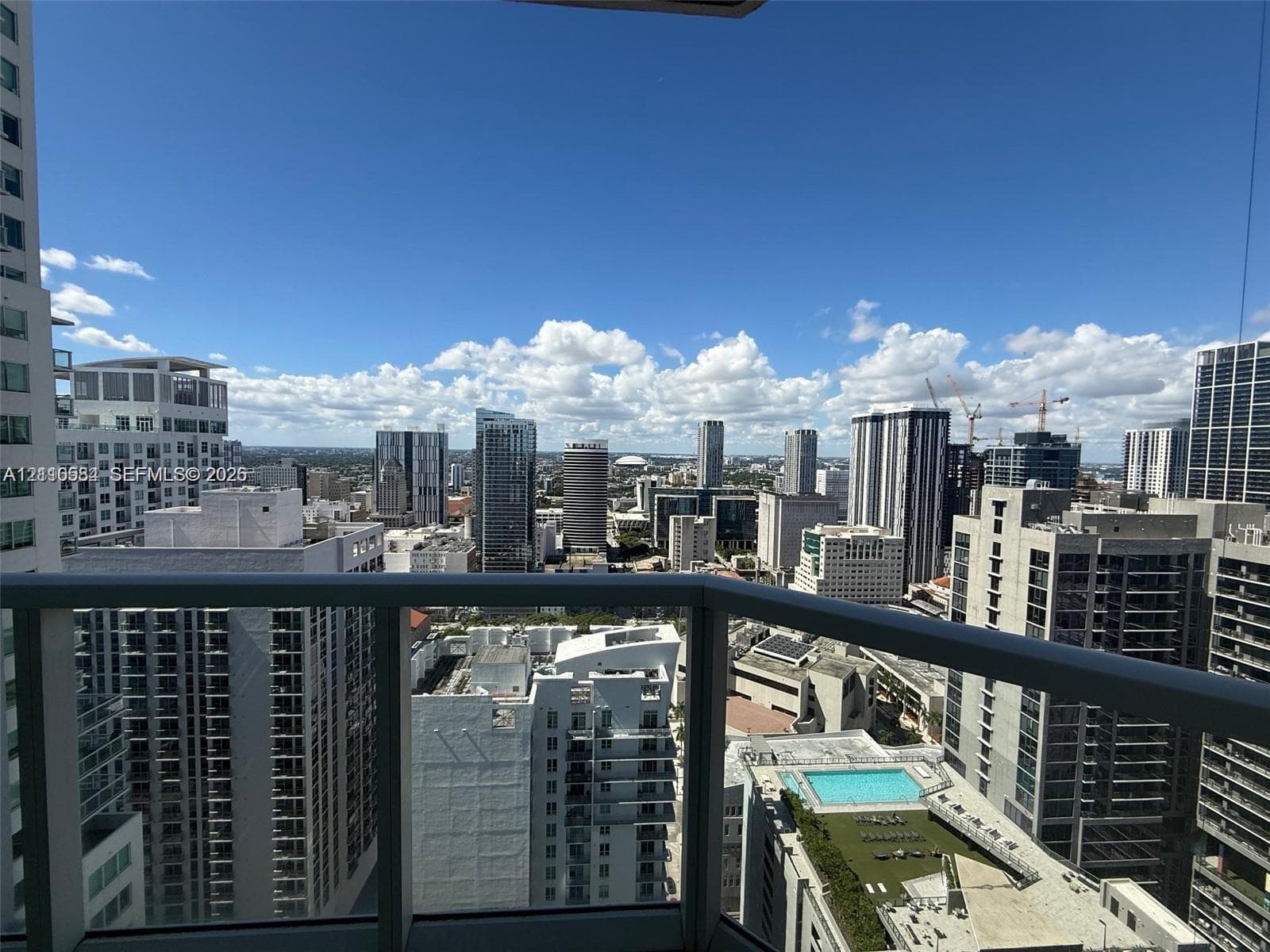 High-rise balcony featuring a glass panel railing and panoramic metropolitan skyline scenery