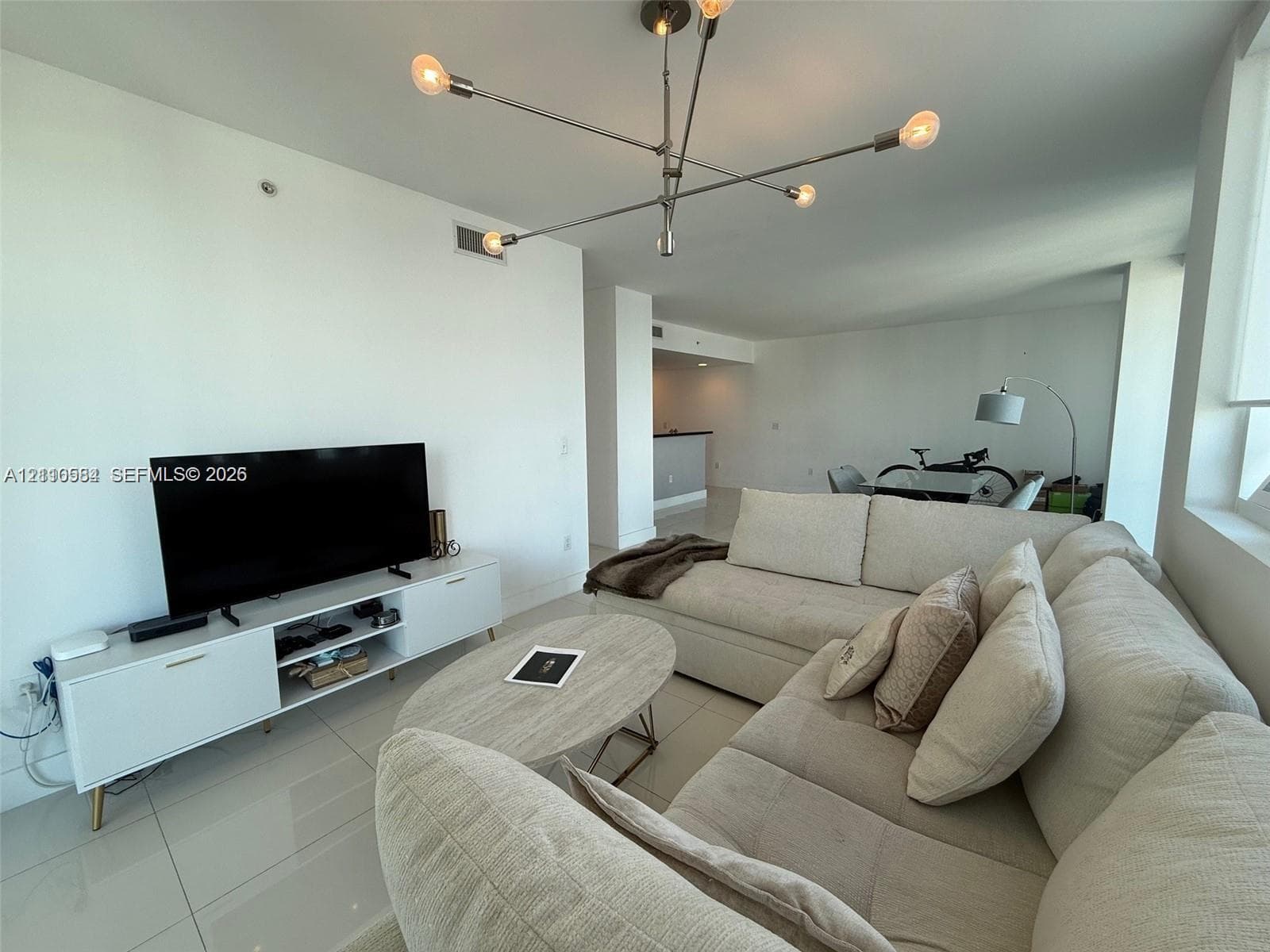 Open-concept interior featuring large-format tile flooring, modern multi-arm sputnik chandelier, and expansive windows