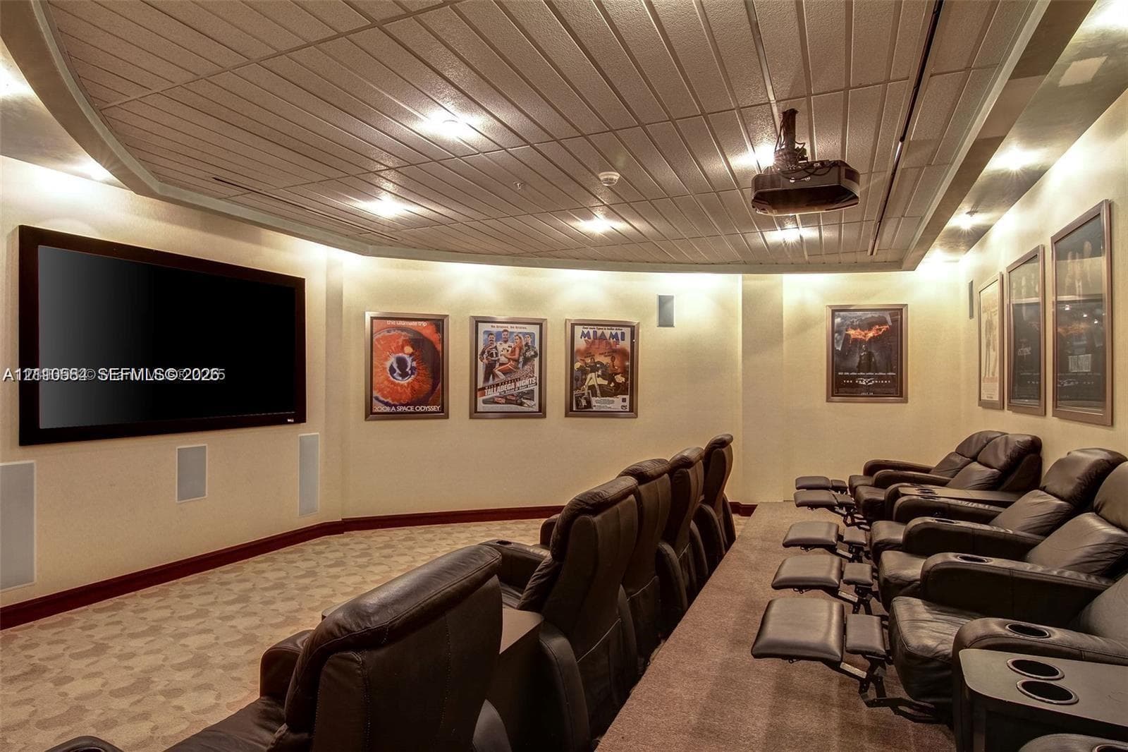 Custom media room featuring a coffered ceiling, recessed lighting, tiered flooring, and integrated wall speakers