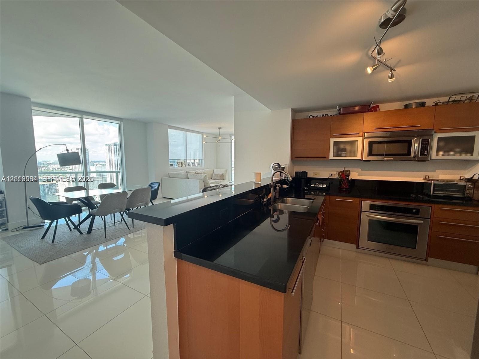 Kitchen featuring wood-finish cabinetry, solid surface countertops, stainless steel appliances, and large-format tile flooring