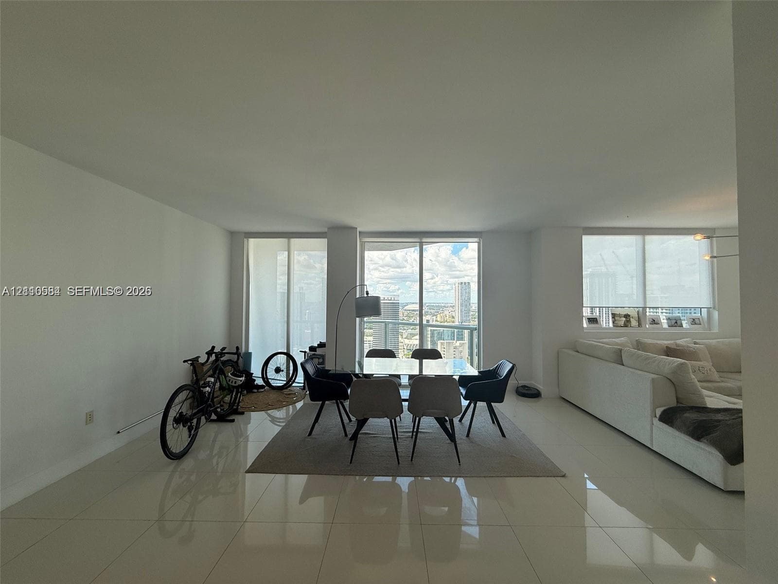 Open-concept living space featuring high-gloss tile flooring, floor-to-ceiling windows, and access to a private balcony
