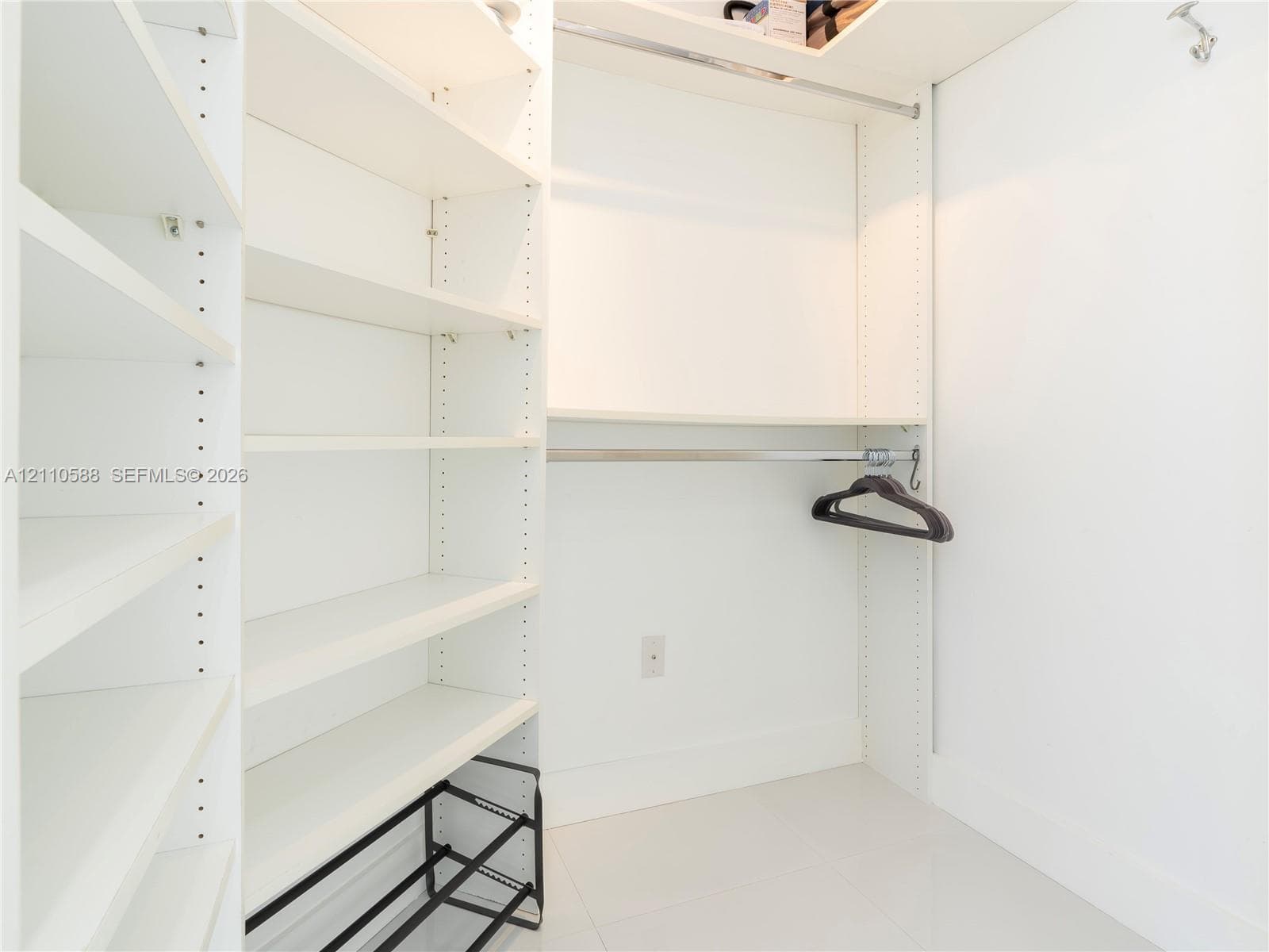 Custom closet organization system featuring adjustable white shelving, hanging rods, and an integrated tiered shoe rack
