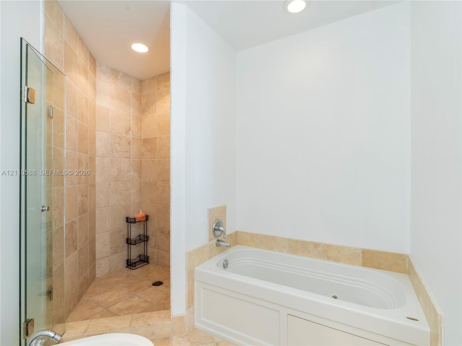 Walk-in shower featuring tile surrounds and a glass enclosure, paired with a deep soaking tub featuring tile surrounds and chrome-finish fixtures
