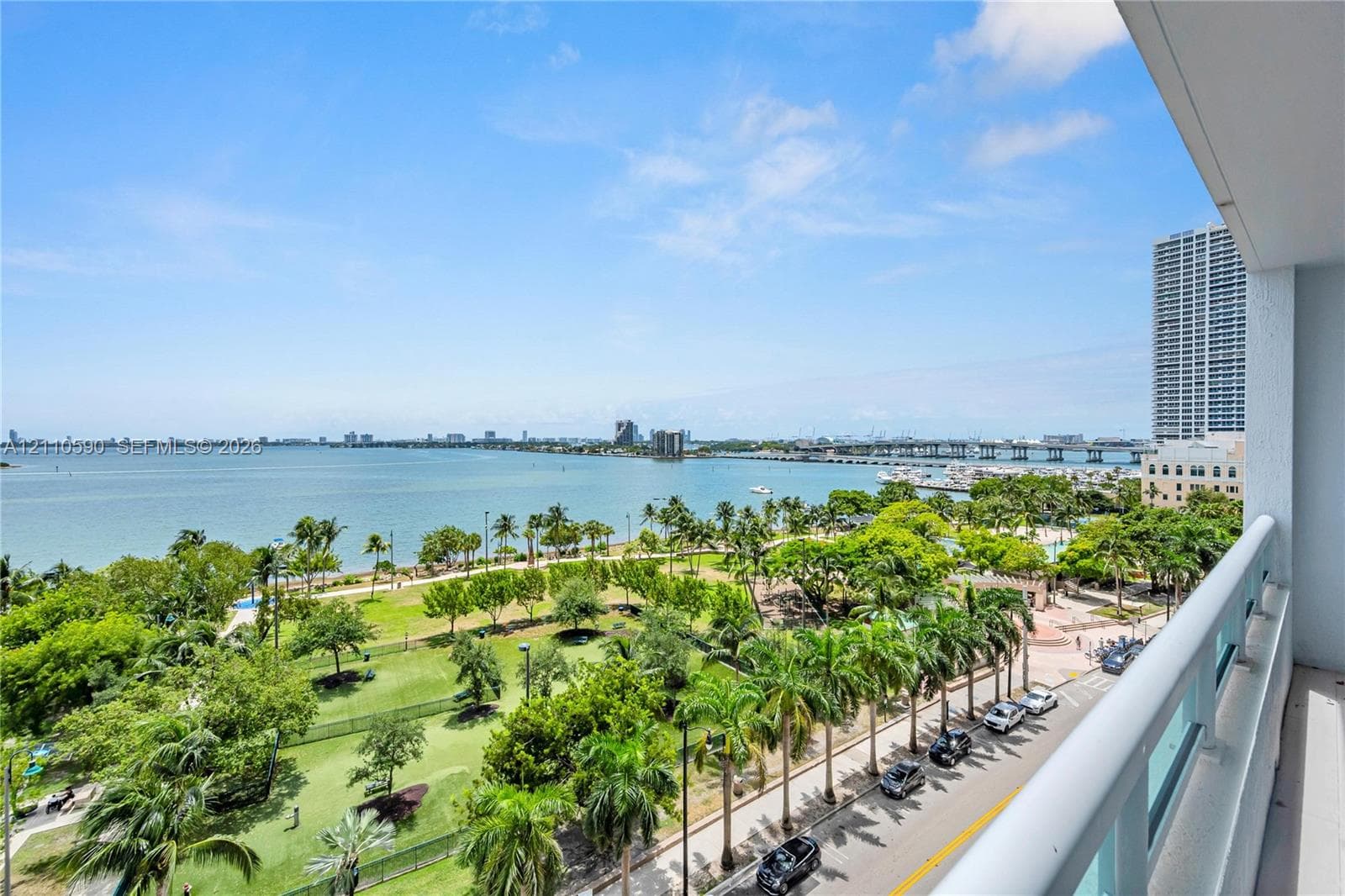 Covered balcony with a glass-panel railing, offering a panoramic outlook over the coastal bay, surrounding parklands, and metropolitan skyline