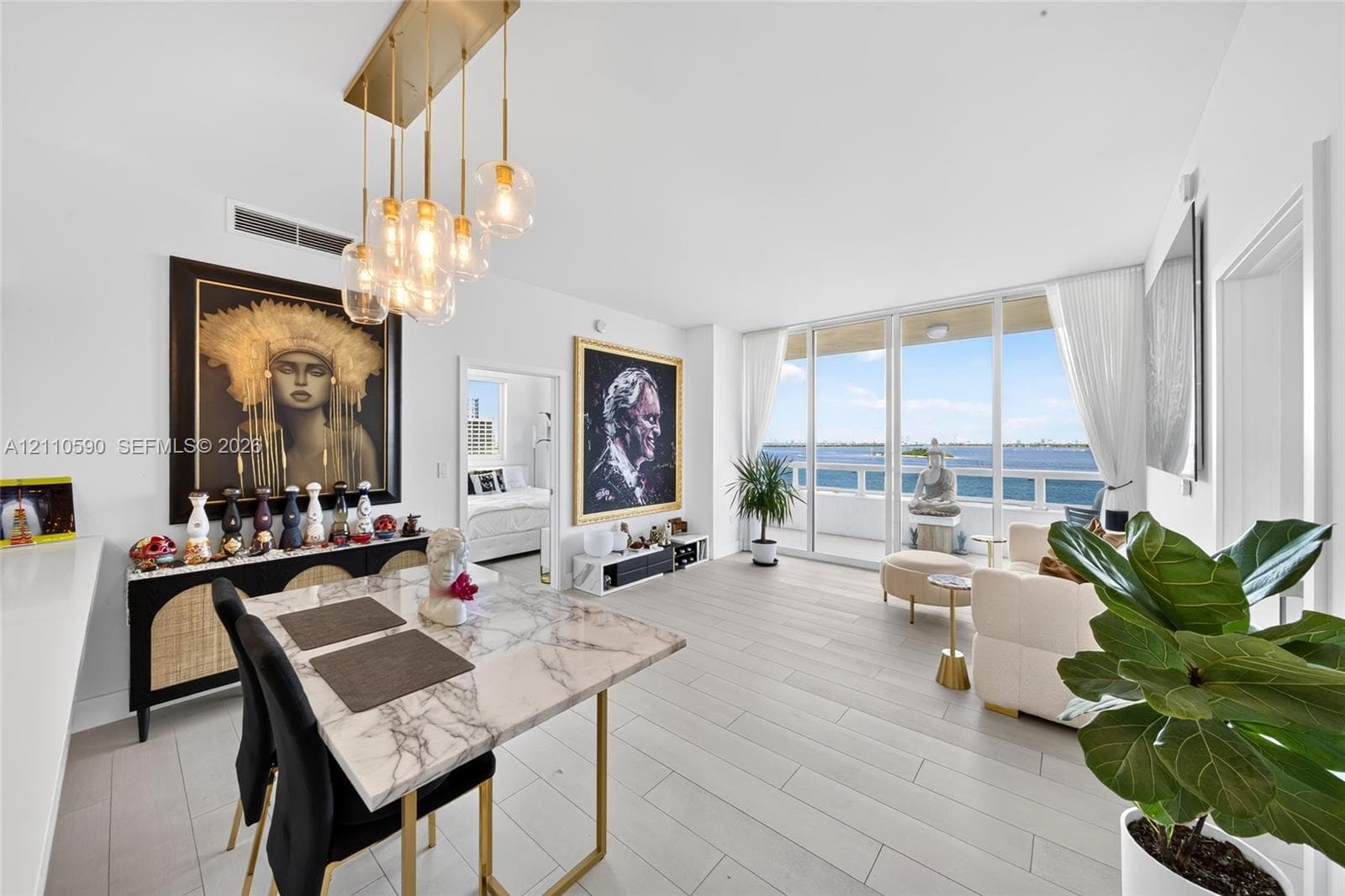 Open-concept living space featuring floor-to-ceiling glass doors, wood-finish flooring, and a multi-pendant gold-tone light fixture