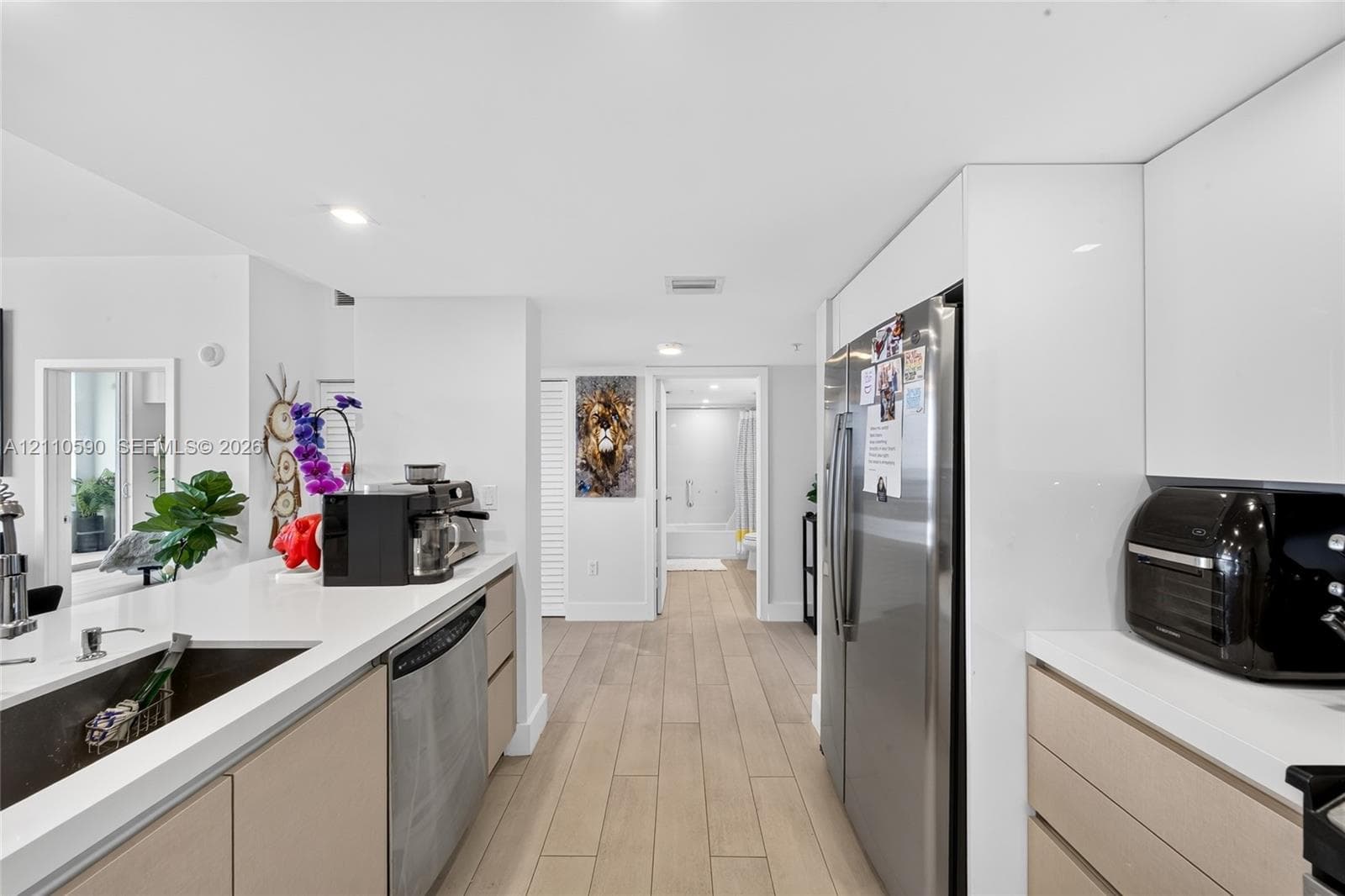 Kitchen featuring flat-panel cabinetry, wood-finish flooring, white countertops, and stainless steel appliances