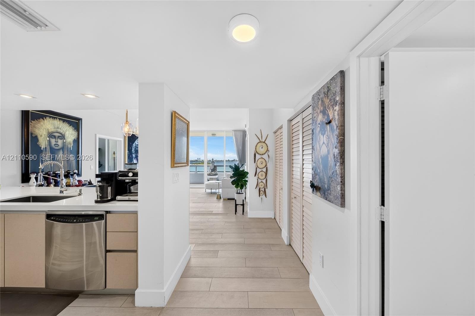 Kitchen featuring flat-panel cabinetry, stainless steel dishwasher, and solid-surface countertop with undermount sink, finished with neutral tile flooring throughout the interior