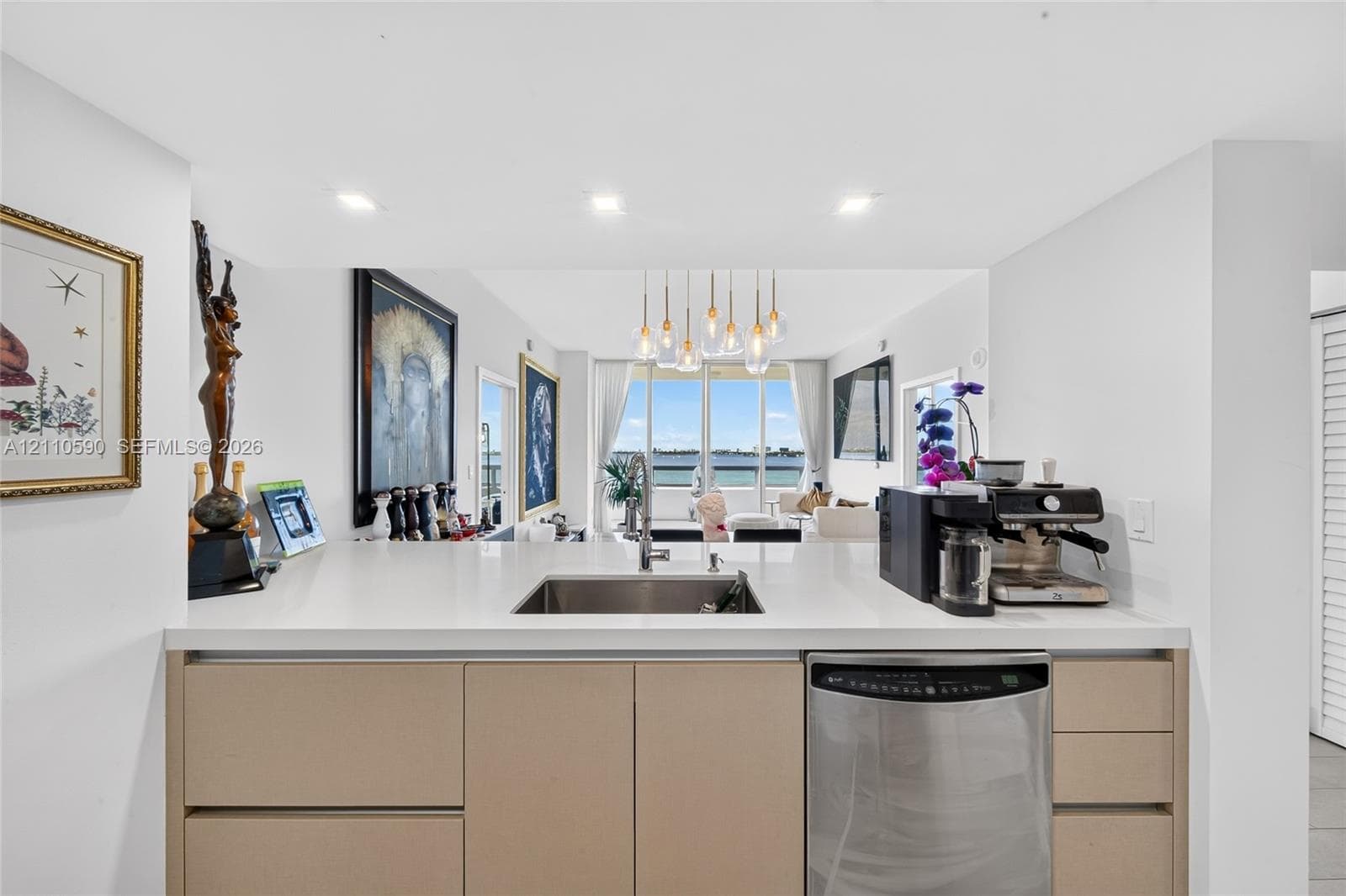Kitchen featuring a quartz countertop, undermount stainless steel sink with a high-arch faucet, sleek flat-panel cabinetry, stainless steel dishwasher, and recessed ceiling lighting