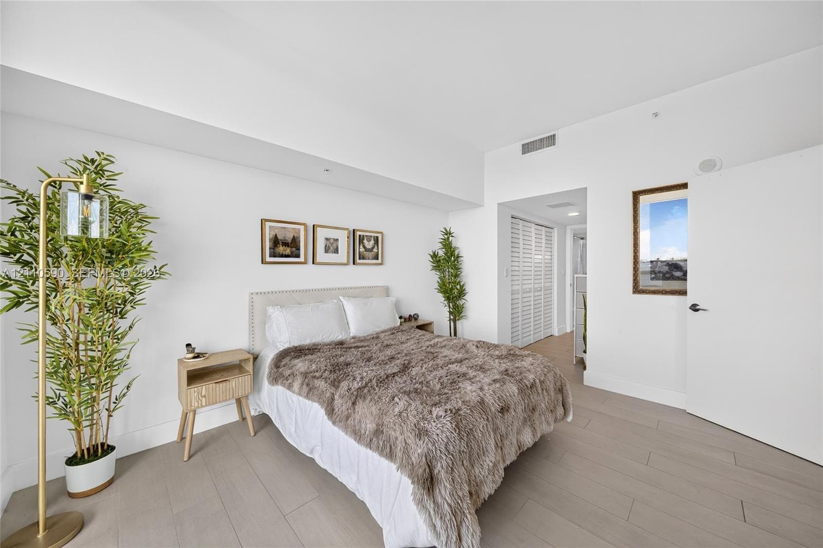 Neutral interior featuring wood-finish flooring, white walls, and louvered closet doors