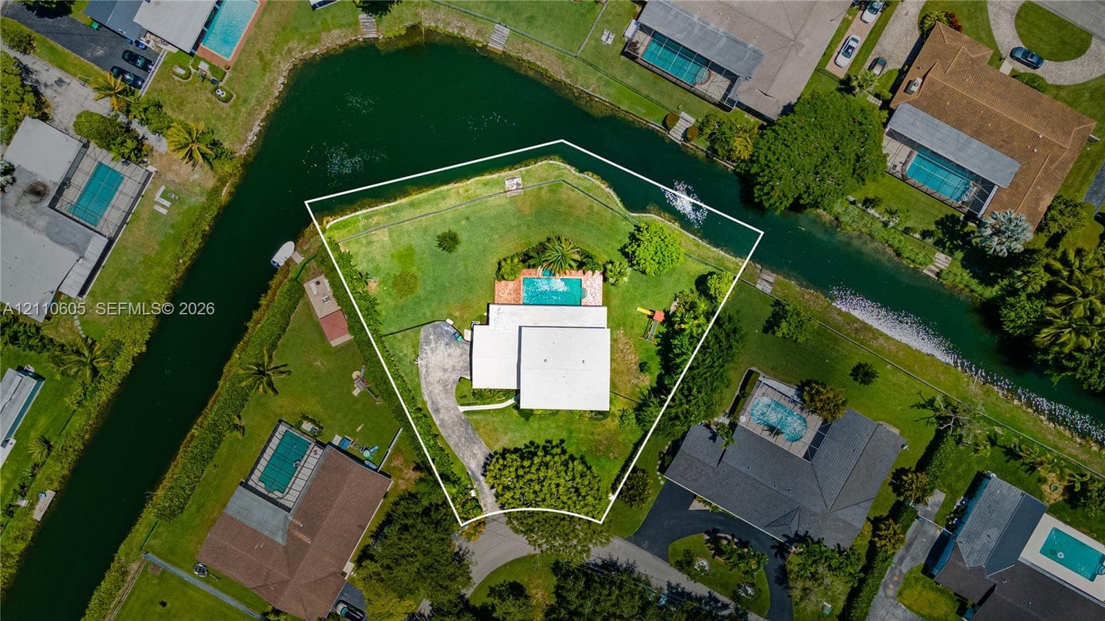Waterfront parcel featuring a corner lot orientation, an inground swimming pool, and mature perimeter landscaping