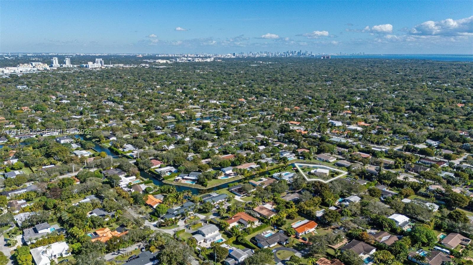 Aerial perspective of a residential property featuring a large lot, perimeter landscaping, and proximity to a canal
