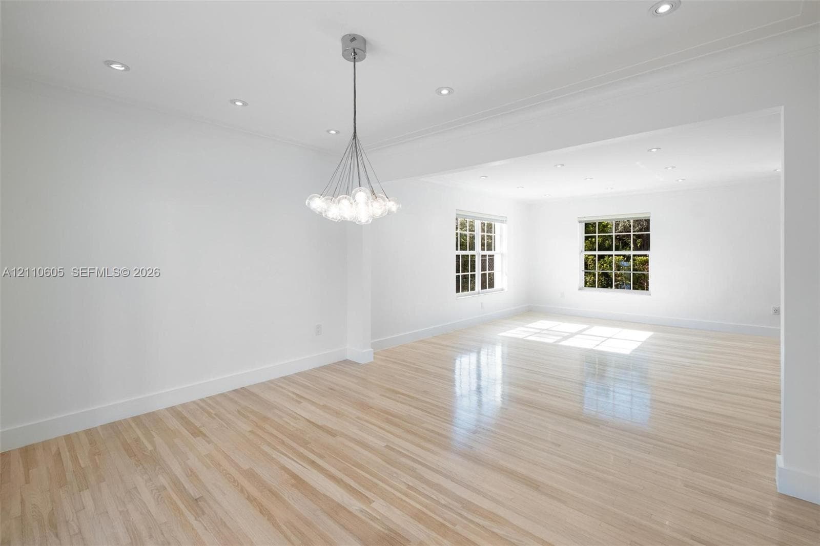 Bright interior featuring wood-finish flooring, multi-pane windows, a contemporary multi-globe pendant light fixture, and recessed lighting