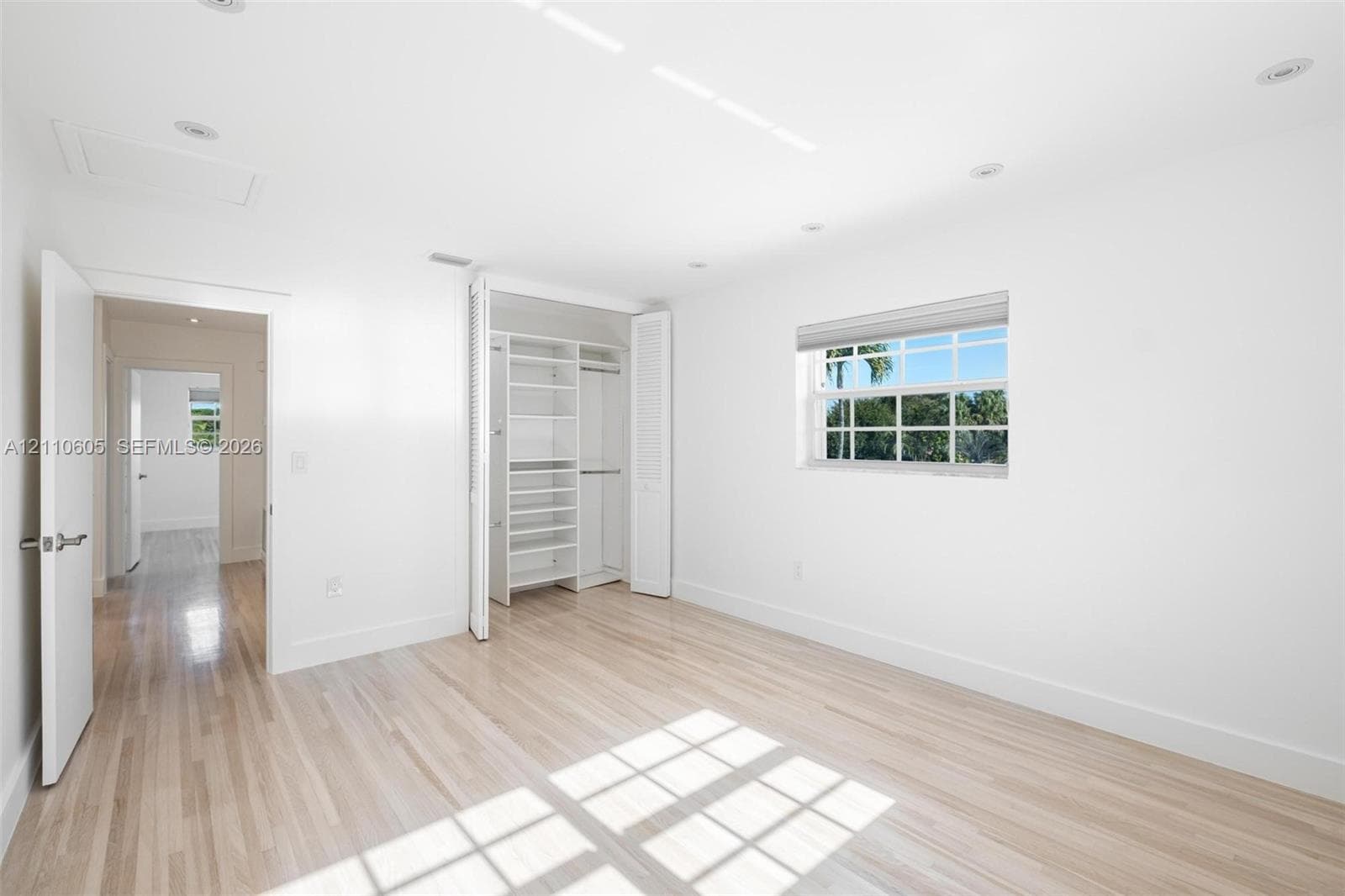 Room featuring light-toned wood-finish flooring, recessed lighting, a single-hung window, and a built-in closet system with open shelving and hanging rods