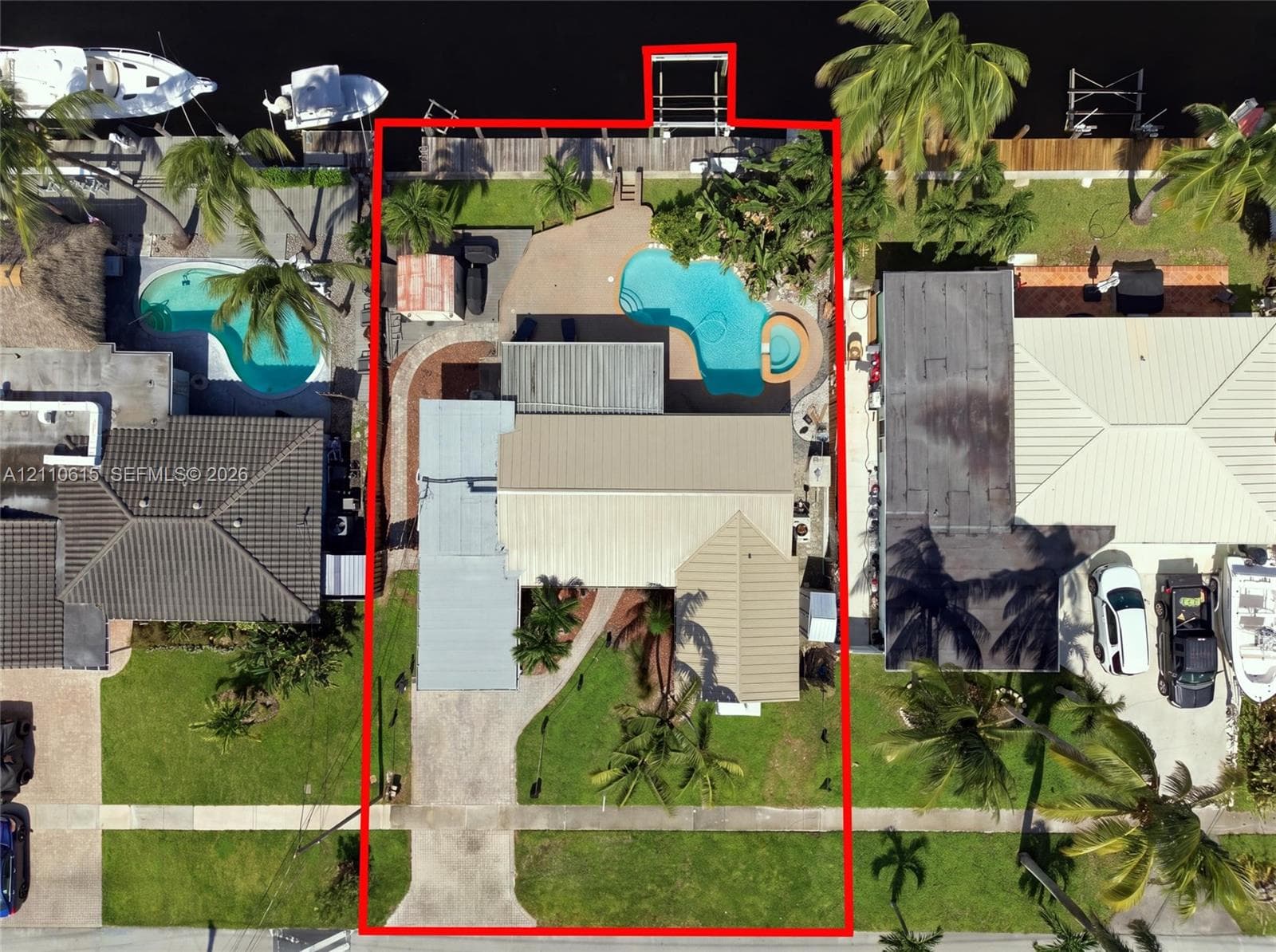 Waterfront property featuring a private boat dock, in-ground swimming pool with integrated spa, concrete patio, and a concrete driveway