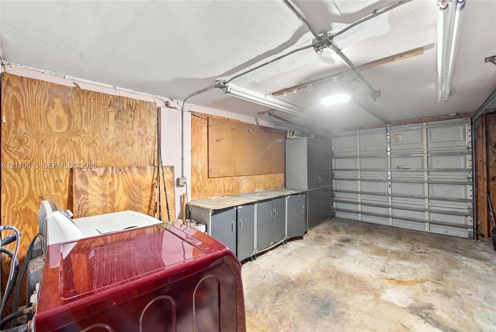 Garage space featuring plywood wall paneling, built-in metal cabinetry, and a sectional overhead garage door