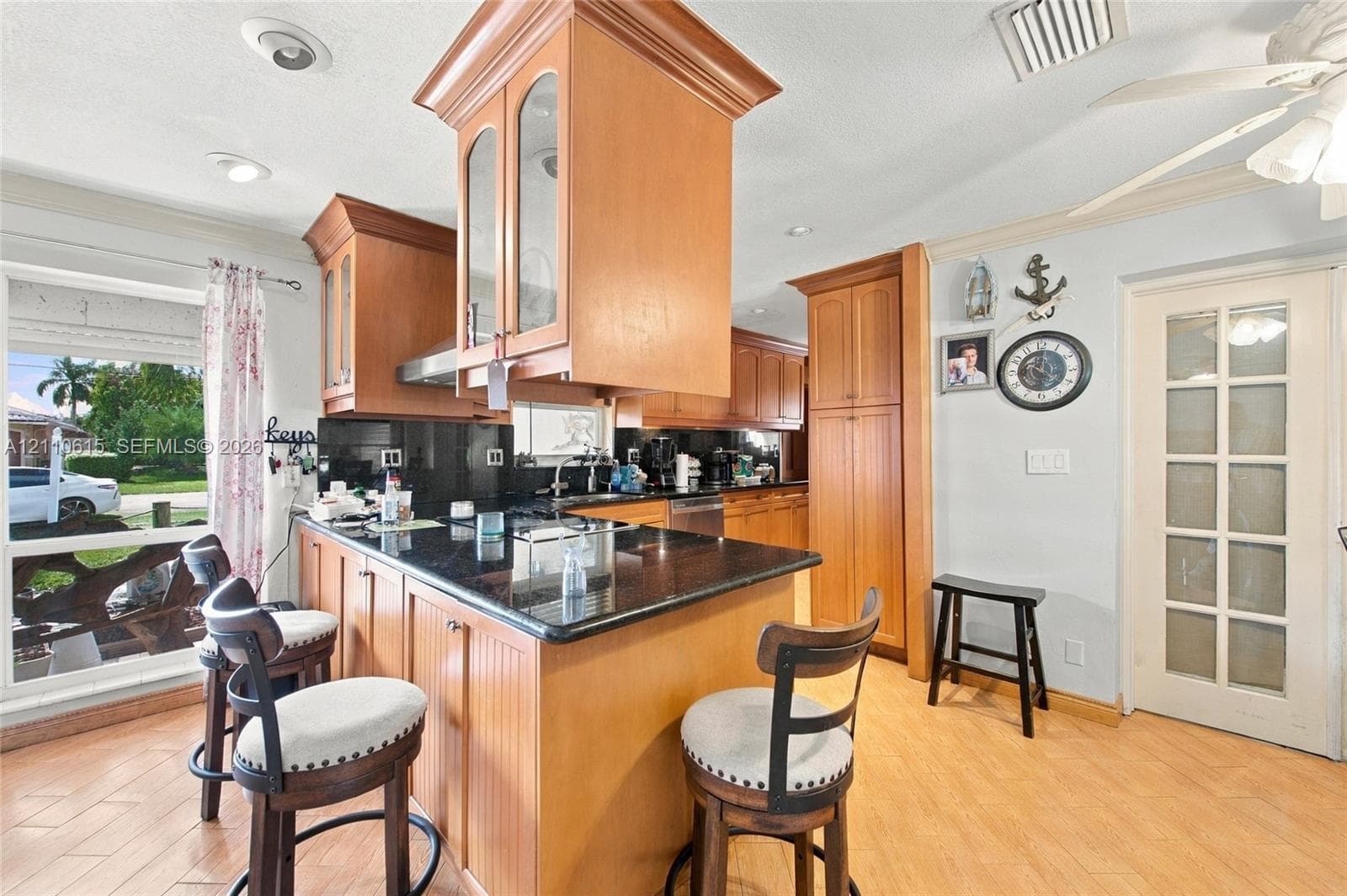 Kitchen featuring wood cabinetry, stone countertops, a large center island, wood-finish flooring, and a multi-pane glass door