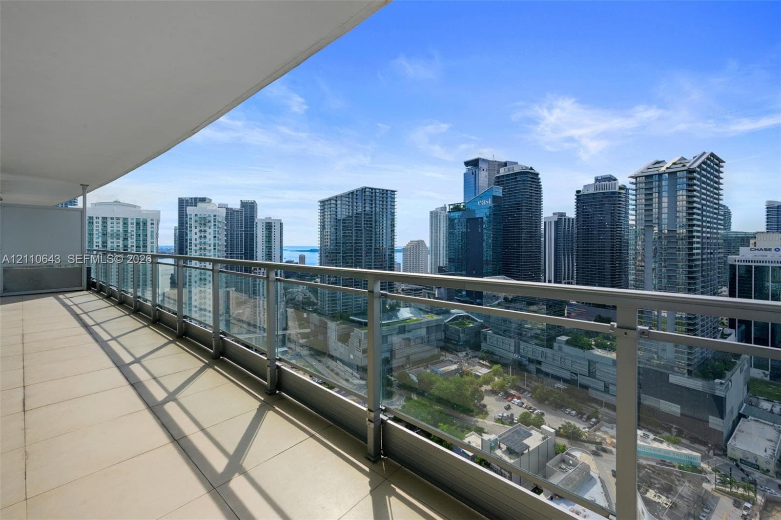 Private balcony featuring large-format tile flooring and a glass panel railing