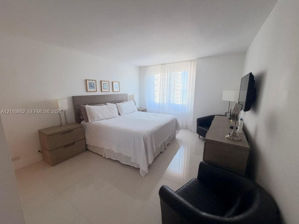 Spacious room featuring polished neutral flooring, a wall-to-wall window treatment, and crisp white wall finishes