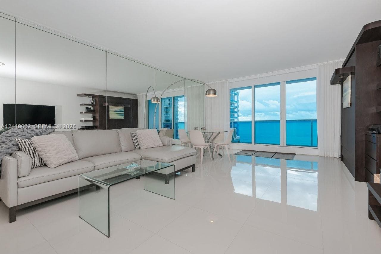 Large picture window with ocean backdrop, light-toned tile flooring, and neutral wall finishes