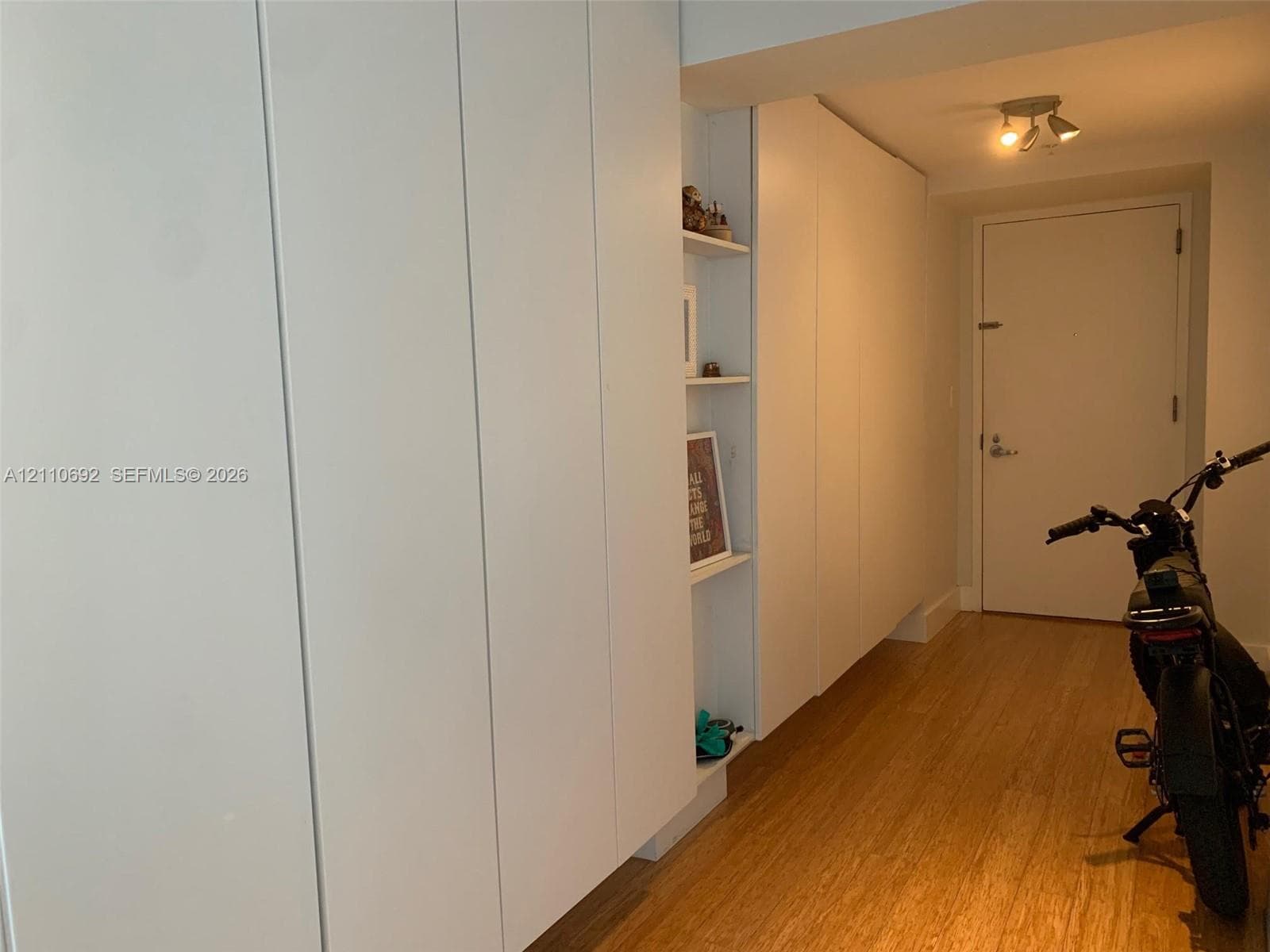 Custom floor-to-ceiling cabinetry featuring integrated shelving, flat-panel white doors, and wood-finish flooring