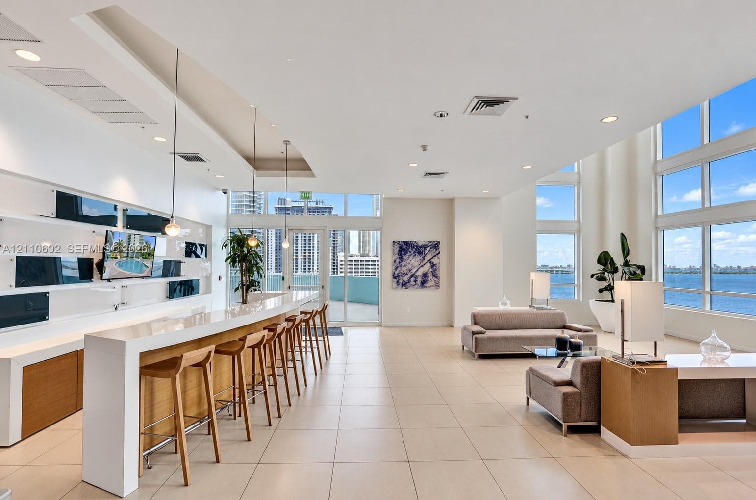 Open-concept interior featuring floor-to-ceiling windows, high-gloss stone-surface bar, recessed lighting, and tile flooring