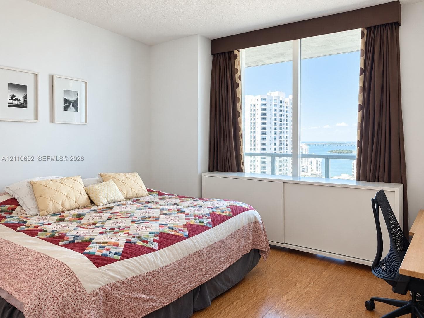 Floor-to-ceiling windows, wood-finish flooring, built-in cabinet console, and balcony access