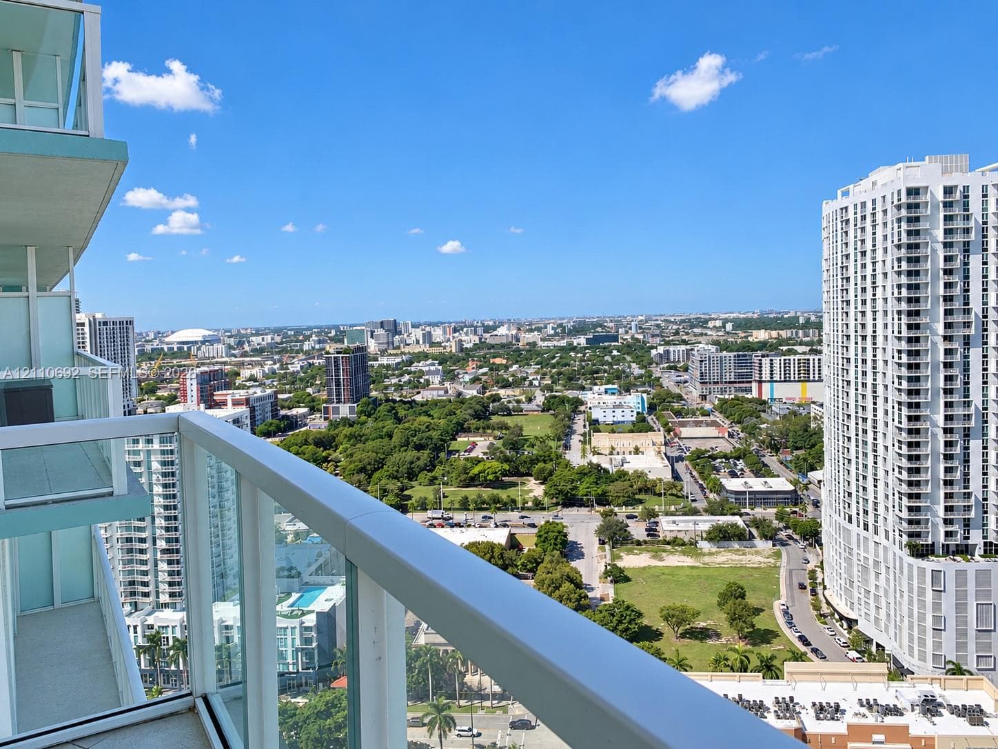 Elevated private balcony featuring glass panel railings and expansive urban scenery