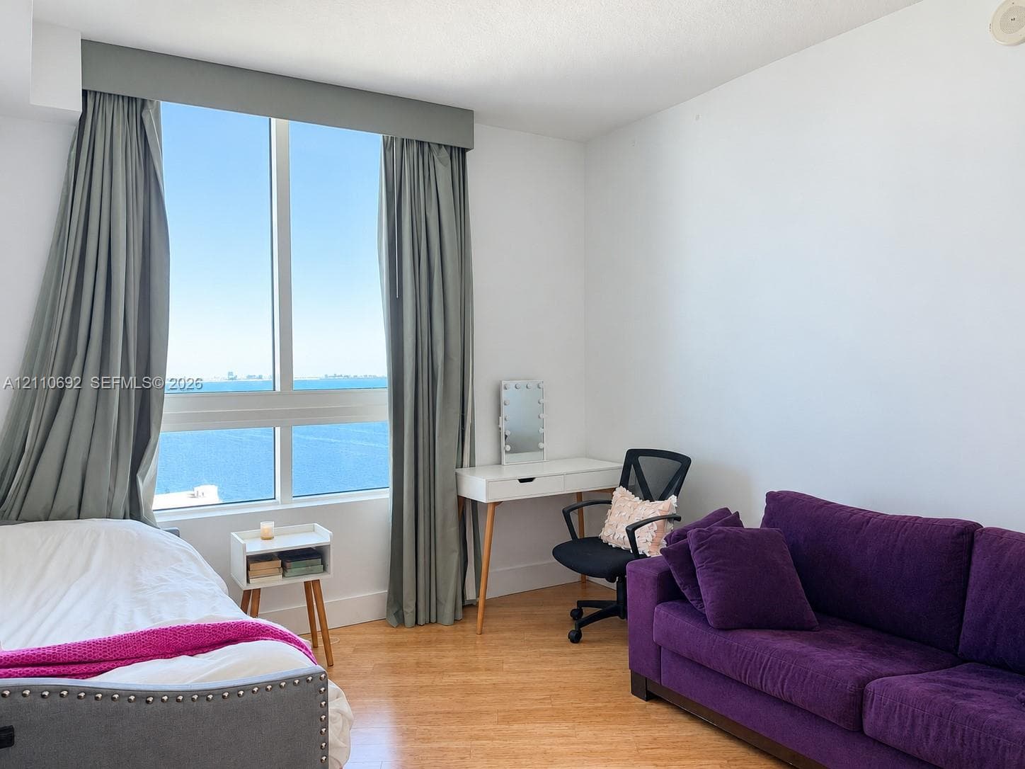 Floor-to-ceiling windows featuring expansive coastal scenery, wood-finish flooring, and a neutral color palette