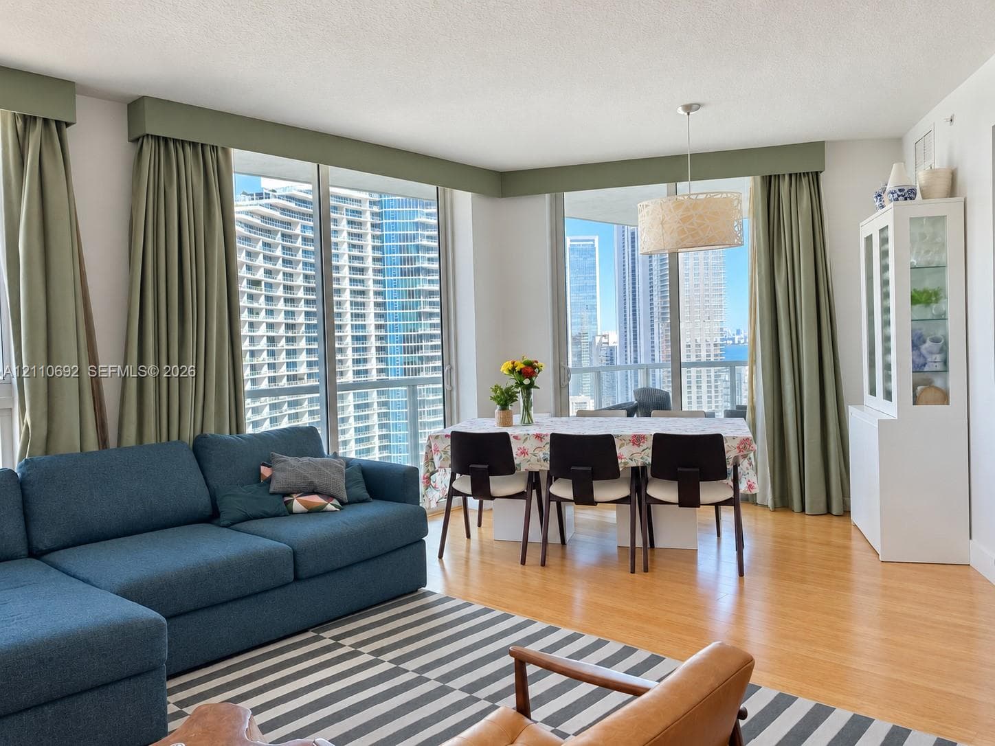 Floor-to-ceiling glass windows, wood-finish flooring, and built-in custom window valances